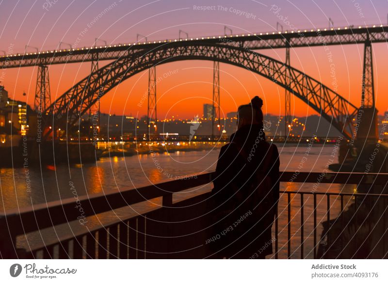 Frau geht bei Sonnenuntergang auf der Böschung Tourist Stauanlage Großstadt Brücke Fluss Borte Wasser Architektur Wahrzeichen Himmel wolkenlos Abend