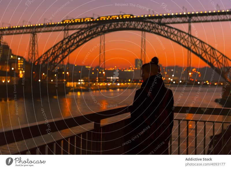 Frau geht bei Sonnenuntergang auf der Böschung Tourist Stauanlage Großstadt Brücke Fluss Borte Wasser Architektur Wahrzeichen Himmel wolkenlos Abend