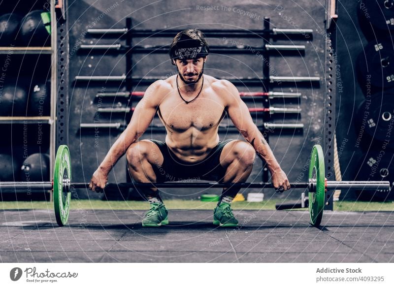starker und sportlicher Mann beim Langhanteltraining in einem modernen Fitnessstudio Curl-Hantel Training Personal Trainerin Heben Gewicht schwer muskulös