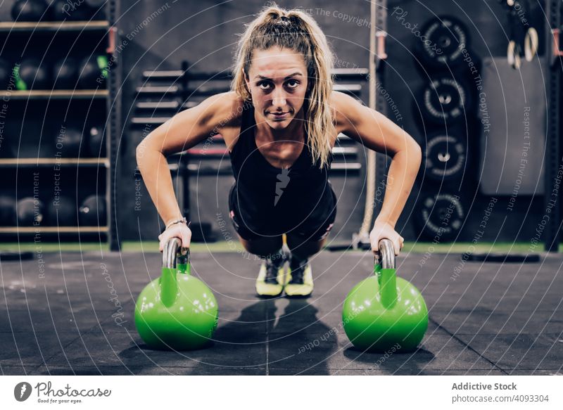 Muskulöse Frau auf Hände in Hanteln in modernen Fitness-Studio auf unscharfen Hintergrund Kurzhantel Fitnessstudio Übung beweglich stark muskulös Sportverein