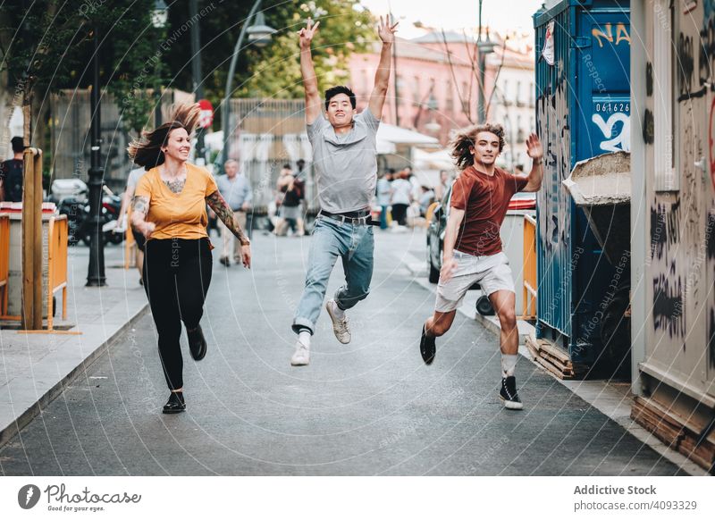 Lustige gemischtrassige Freunde, die Spaß haben und durch die Stadt laufen so tun, als ob Zusammensein Straße vielfältig Großstadt lustig Lächeln