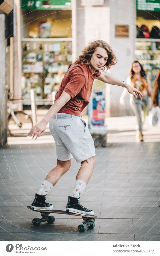 Selbstbewusster Mann fährt mit seinem Longboard über eine Straße in der Stadt Mitfahrgelegenheit Großstadt urban Freestyle Trick fokussiert lässig cool