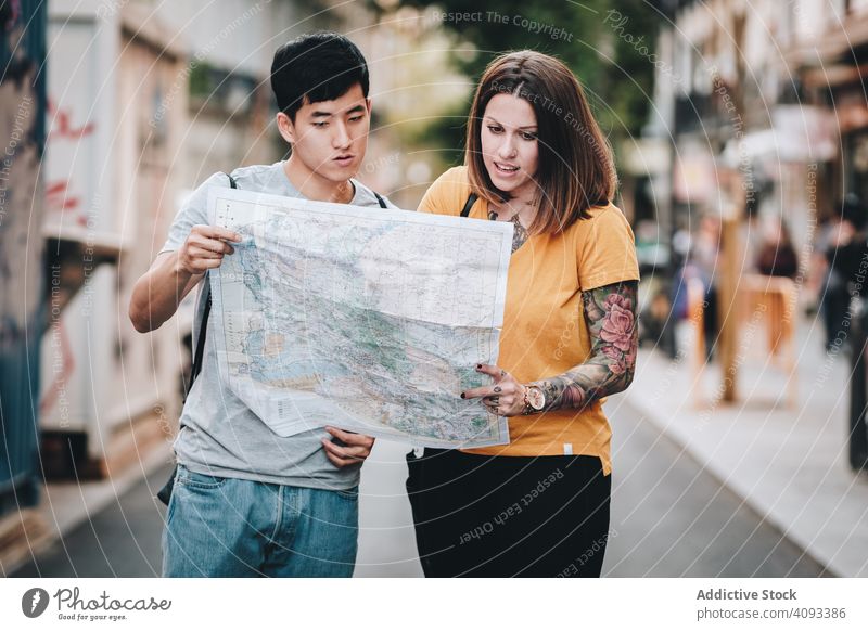 Fröhliche multirassische Touristen, die auf der Straße stehen und den Stadtplan prüfen Landkarte freudig Spaß verirrt Lachen urban Großstadt Regie Beteiligung