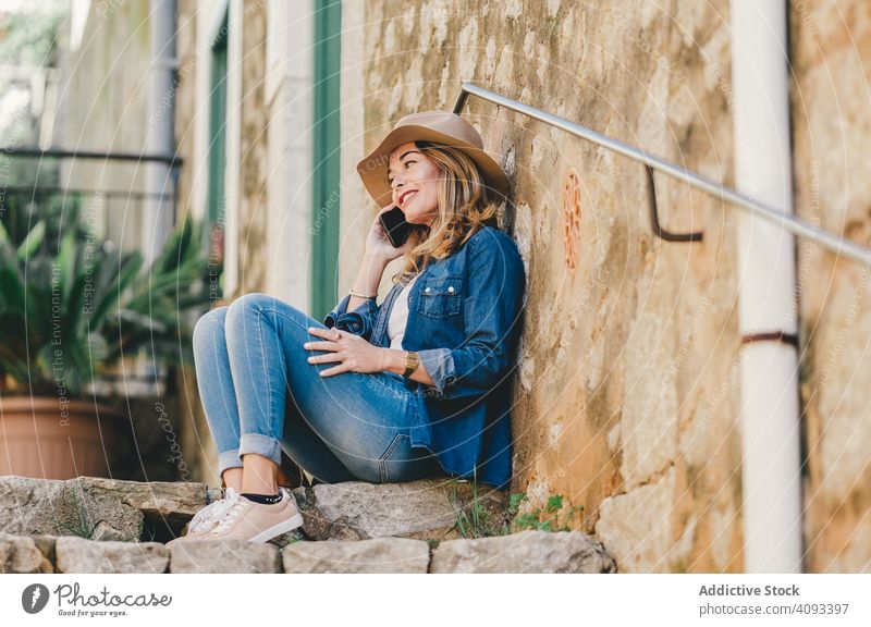 Frau mit Smartphone sitzt auf Steinstufen einer Treppe Glück schön sprechend attraktiv charmant Erholung Straße selbstbewusst Model Mitteilung nachdenklich