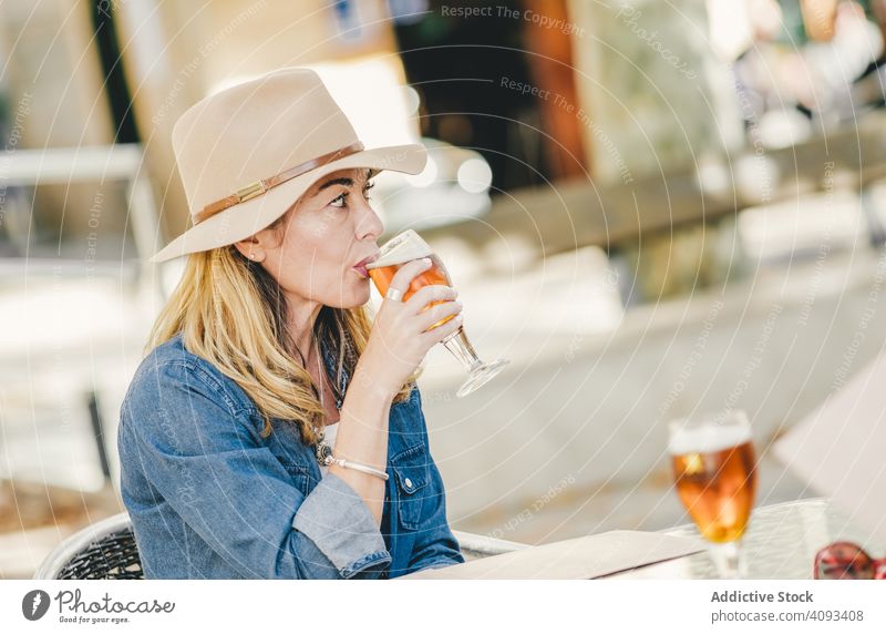 Schöne Frau trinkt sitzend in einem Straßencafé trinken Bier schön charmant Café Erholung Glas Glück selbstbewusst Model Lächeln lieblich Lagerbier Getränk