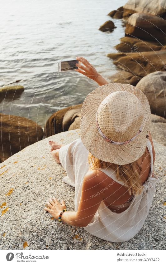Zeitgenössische Frau mit Telefon, die am Meer chillt Meeresufer Smartphone Küste Kälte allein genießen Flucht reisen Seeküste Einsamkeit abgelegen Drahtlos