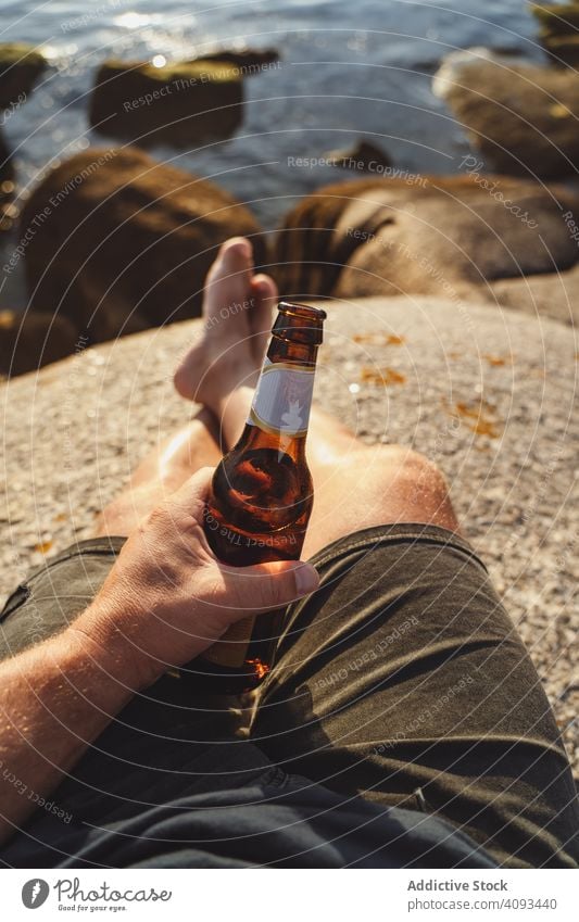 Bierflasche in der Hand mit Meereslandschaft im Hintergrund Mann MEER Barfuß Küste Sonnenlicht Flasche jubelt Seeküste Alkohol Strand durch Erfrischung Party
