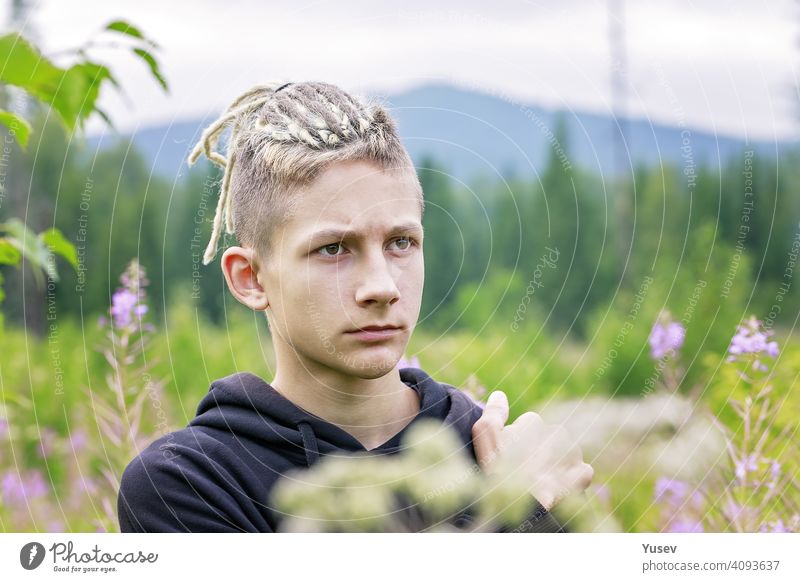 Junge gut aussehende Mann steht in der Mitte der wilden Feld von Blumen. Sommer-Aktivität, Urlaub in den Bergen, Wandern, gesunden Lebensstil. jung gutaussehend
