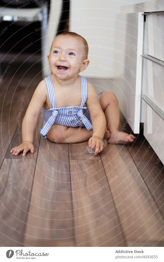 Glückliches Baby sitzt auf dem Boden in der Küche Stock sitzen heimwärts gemütlich Abfertigungsschalter Parkett Spaß Kind Kleinkind Kindheit Barfuß aufgeregt