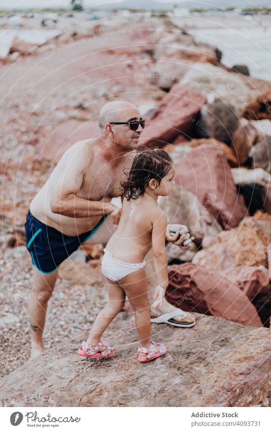 Grossvater und Enkelin amüsieren sich am felsigen Strand Urlaub Großvater Meer Familie älter Kind Mädchen Wasser Natur Ufer genießend in den Ruhestand getreten
