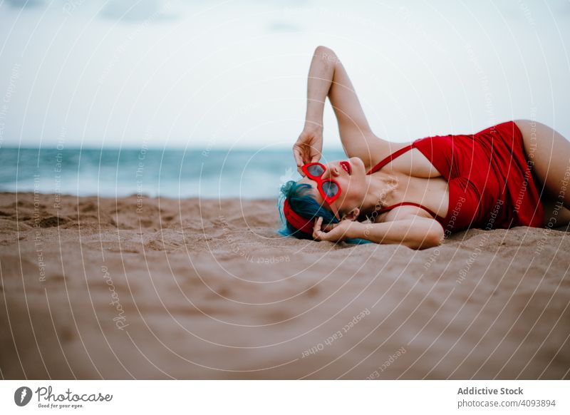 Entspannte Frau im hellen stilvollen Badeanzug am Sandstrand liegend Strand stylisch MEER retro Lügen Erwachsener sandig sinnlich Erholung Mode altehrwürdig