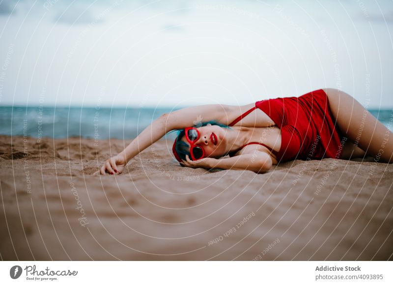 Entspannte Frau im hellen stilvollen Badeanzug am Sandstrand liegend Strand stylisch MEER retro Lügen Erwachsener sandig sinnlich Erholung Mode altehrwürdig