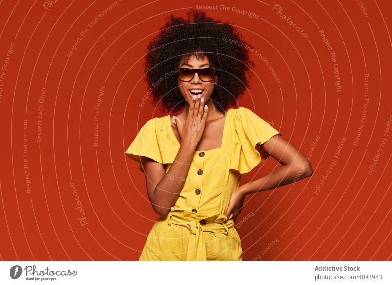 Helle ethnische Frau mit Händen hinter dem Kopf, die in die Kamera lächelt trendy farbenfroh hell Inhalt modern cool Dame schwarz selbstbewusst Farbe Model