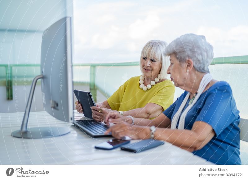 Ältere Frauen benutzen Tablet in der Nähe des Computers benutzend Tablette älter Freund Tisch Balkon Resort soziale Netzwerke Senior reif Zusammensein