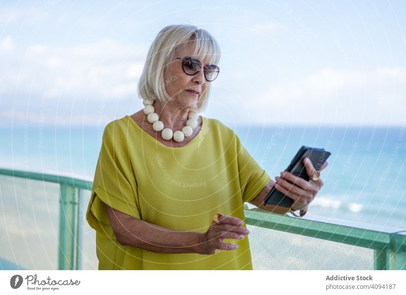 Ältere Dame benutzt Smartphone auf Hotelterrasse Frau Balkon benutzend MEER Resort älter stylisch in den Ruhestand getreten sich[Akk] entspannen ruhen Lifestyle