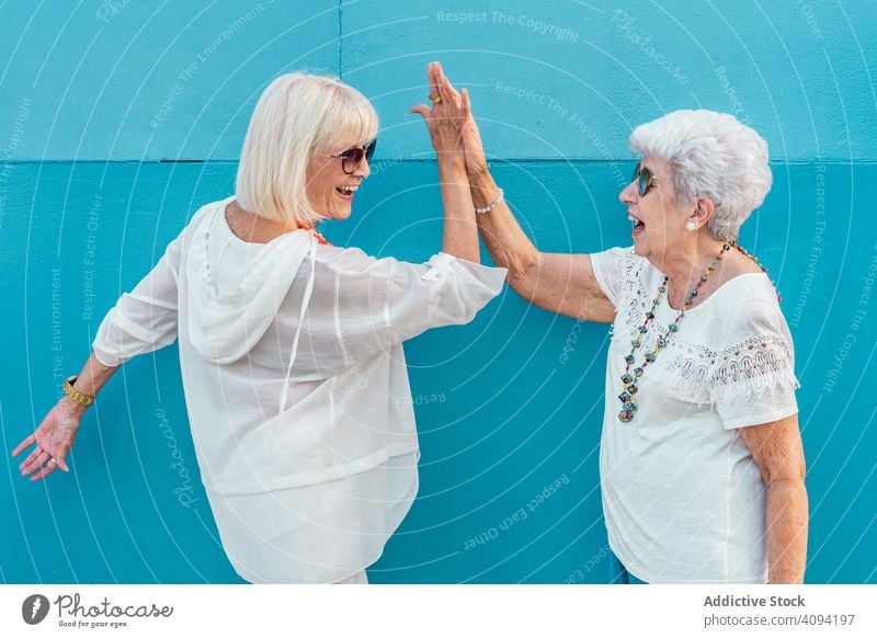 Ältere Freundinnen geben sich die Hand gealtert Freunde high five Senior Frauen älter Lachen positiv optimistisch heiter feiern Gruß Erfolg Fröhlichkeit