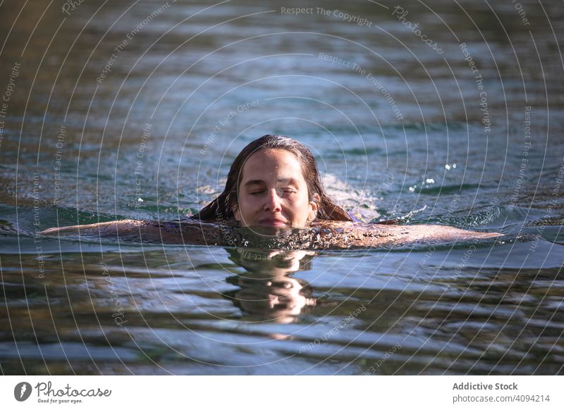Frau schwimmt mit geschlossenen Augen im See schwimmen geschlossene Augen Spa Wasser Erwachsener Freude sonnig tagsüber Teich platschen Herbst Saison fallen