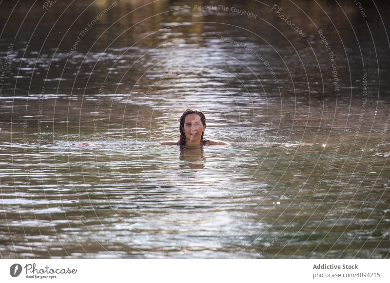 Frau schwimmt in einem See und schaut in die Kamera schwimmen Spa Wasser Erwachsener Freude sonnig tagsüber Teich platschen Herbst Saison fallen Resort Natur