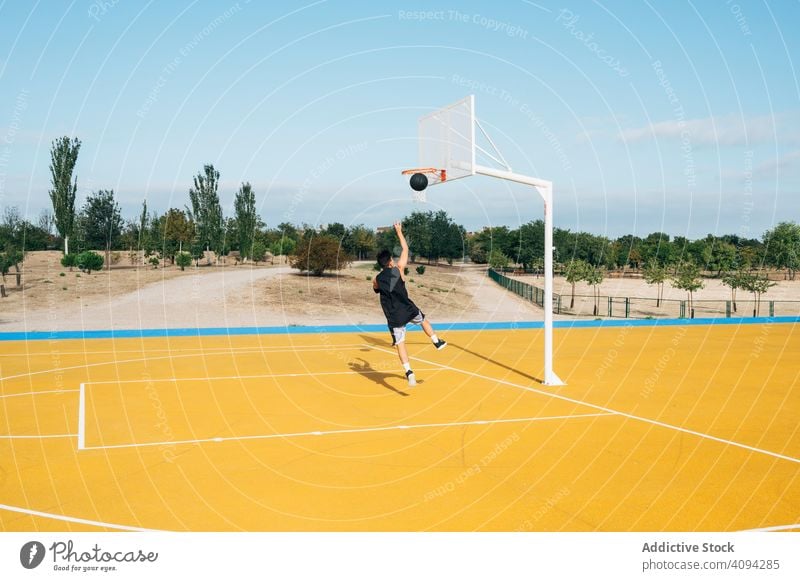 Junger Mann spielt auf gelbem Basketballfeld im Freien. Athlet Konkurrenz Sportgerät Erwachsener Erholung Aktion Ball Porträt aktiv Aktivität Asphalt sportlich