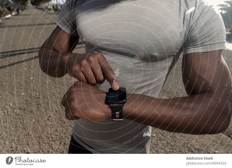 Ethnischer Sportler benutzt Tracker auf der Straße verwenden intelligente Uhr laufen sportlich ethnisch Start Vorbereitung Gerät Apparatur tragbar männlich
