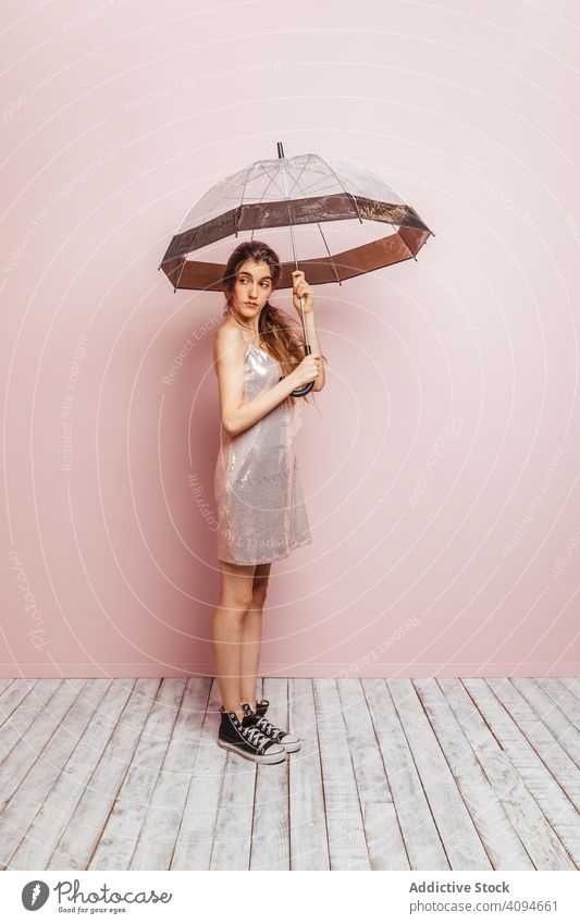 Junges Mädchen posiert mit einem Regenschirm auf rosa Hintergrund Sommer Frühling im Innenbereich Zubehör Sonnenschirm Raum Kopie Blick Frauen Konzept Schutz