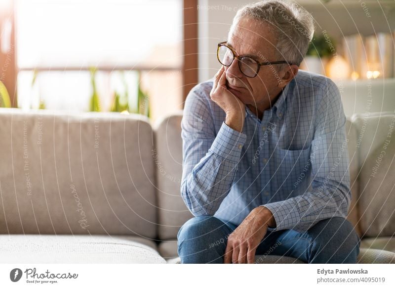 Besorgter älterer Mann sitzt allein in seinem Haus Menschen eine Person Senior reif Rentnerinnen in den Ruhestand getreten alt graues Haar Kaukasier Erwachsener