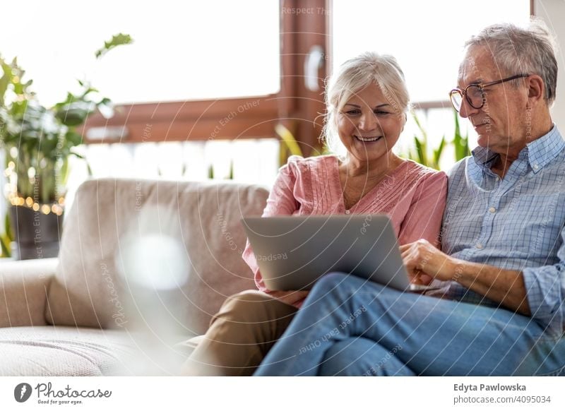 Reifes Paar verwendet einen Laptop beim Entspannen zu Hause Menschen Frau Erwachsener Senior reif lässig attraktiv männlich Mann Lächeln Glück Kaukasier