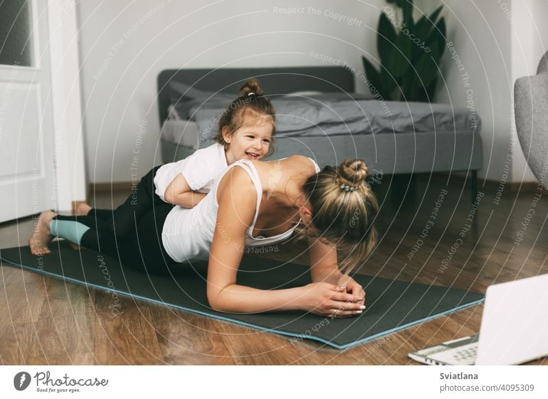 Eine junge sportliche Mutter und ein Mädchen machen zusammen Übungen zu Hause. Gesunde Entwicklung von Eltern und Kindern, gesunder Lebensstil Frau Fitness