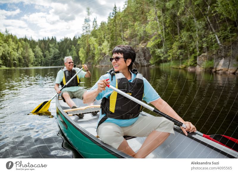 Glückliches reifes Paar in Rettungswesten Kanufahren im Waldsee. Sonniger Sommertag. Touristen, die in Finnland reisen und Abenteuer erleben. aktiv Aktivität