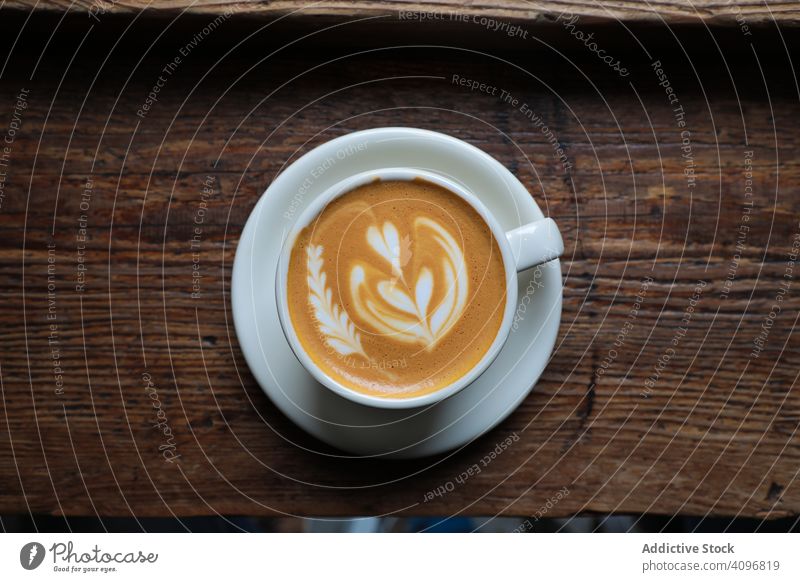 Leckerer heißer Kaffee mit Latte Art Kunst Cappuccino Tasse Bierschaum Café Kaffeehaus Aroma lecker trinken schäumen melken Getränk Tisch serviert Herz rosetta