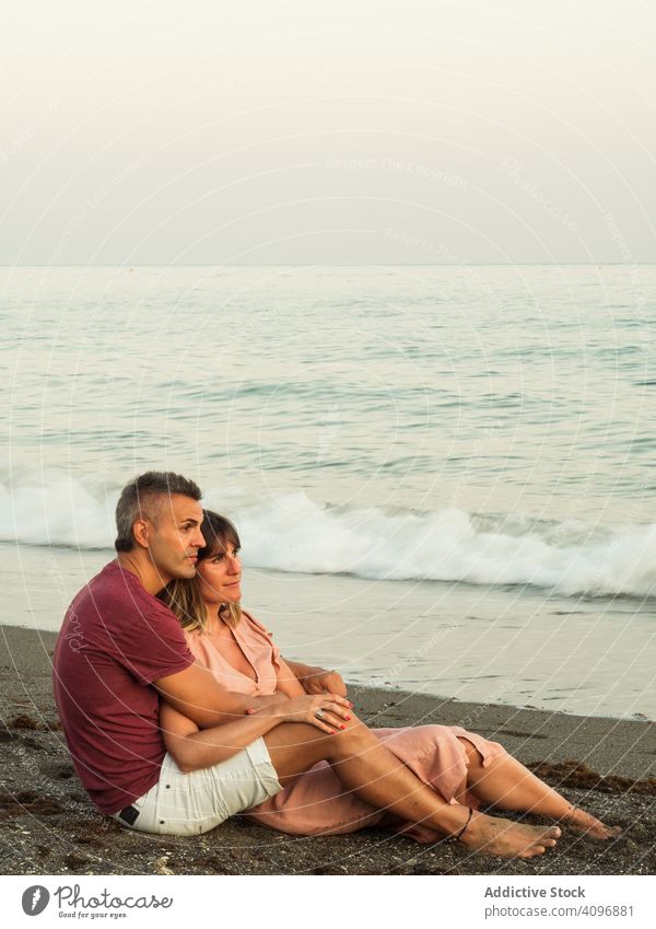 Freudiges Paar sitzt am Strand Resort Liebe Umarmung Termin & Datum sitzen MEER Lächeln Glück Urlaub Mann Frau Erwachsener Flitterwochen Sommer Ufer Küste