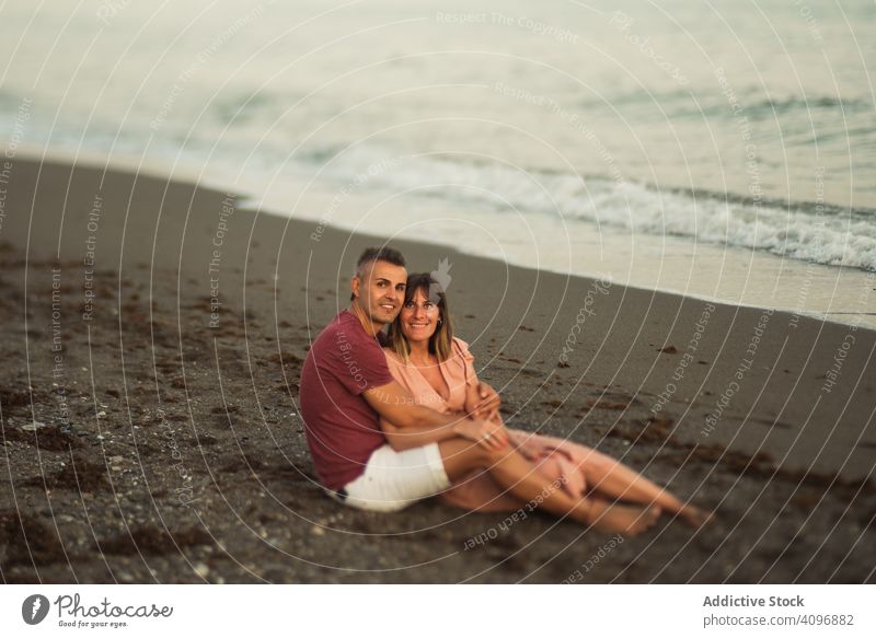 Freudiges Paar sitzt am Strand Resort Liebe Umarmung Termin & Datum sitzen MEER Lächeln Glück Urlaub Mann Frau Erwachsener Flitterwochen Sommer Ufer Küste