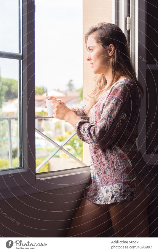 Mädchen im Hemd mit einer Tasse Kaffee oder Tee, das morgens aus dem Fenster schaut Frau hübsch wach Freude Schönheit im Innenbereich Ansicht heimwärts ruhen