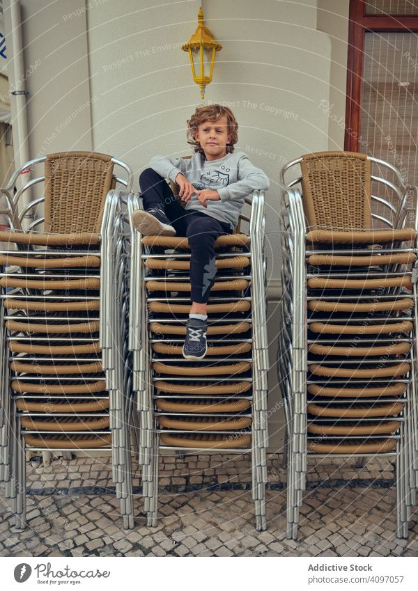Wehmütiger Junge entspannt sich auf einem Sessel auf der Terrasse sich[Akk] entspannen Straße Armsessel ruhen Stuhl besinnlich wehmütig Kind bequem Portugal