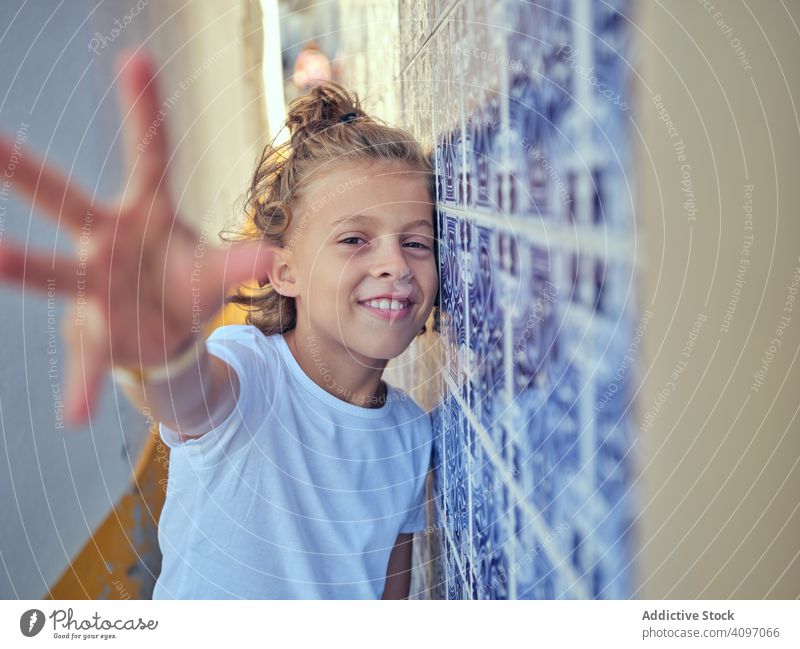 Lächelndes Kind auf der Straße stehend Portugal Inhalt Stehen fettarm Wand Glück Kindheit Sonnenlicht Freizeit heiter jung sich[Akk] entspannen ruhen Urlaub