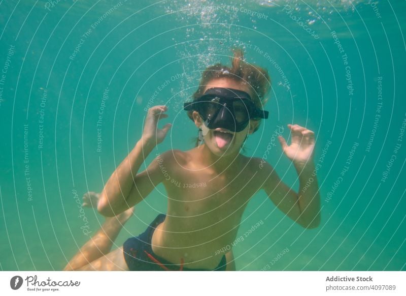 Verspielter Junge mit Maske schwimmt unter Wasser Sinkflug Spaß ausspannen Mundschutz aktiv MEER Grimasse Kind konfrontierend durchsichtig Schwimmer