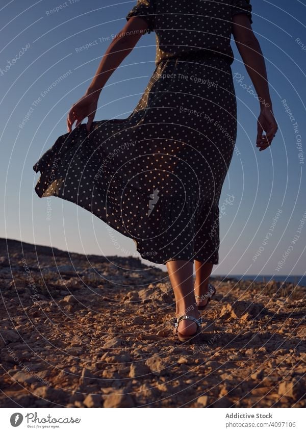 Frau, die am Strand spazieren geht, während der Wind ihr Kleid weht Fußknöchel MEER laufen Sommer Seeküste Bein Urlaub Abenteuer Meer schön Feiertag Mode