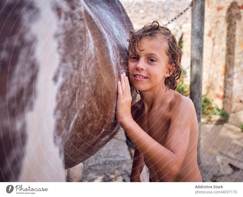 Freudiger Junge streichelt Hengst Pferd Umarmen streicheln Liebe Ranch Harmonie Glück erfreut Kind Behaarung Pflege lockig nass Seite Landschaft Pferderücken