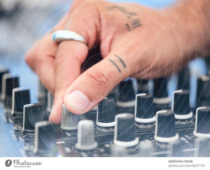 Anonymer DJ, der während der Party Musik auflegt dj Melodie Audioboard Mixer Arbeit Tattoo Club Schauplatz Entertainment Klang Schaltfläche drehen. Hand
