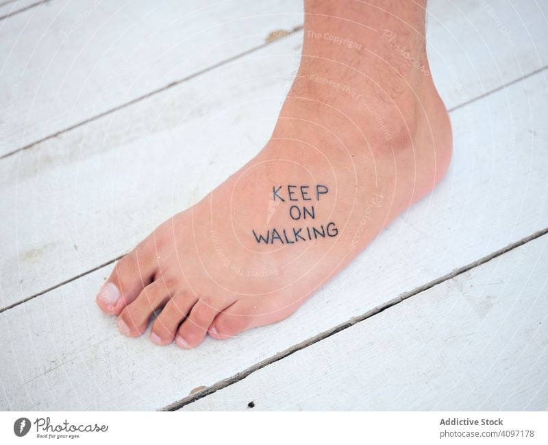 Fuß mit Motivations-Tattoo auf Holzboden Person schreibend Stock stehen Barfuß weitergehen Pier hölzern weiß Inspiration Resort Aufschrift Bein Körperteil
