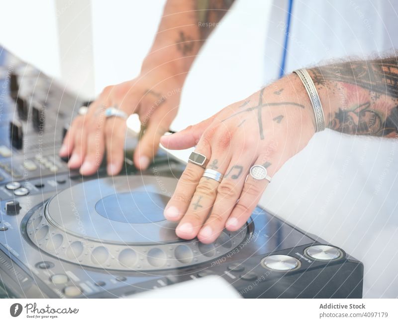 Anonymer DJ, der während der Party Musik auflegt dj Melodie Audioboard Mixer Arbeit Tattoo Club Schauplatz Ringe Entertainment Klang Schaltfläche drehen. Hand