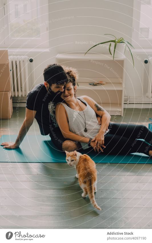 Verliebtes Paar kuschelt auf dem Boden, während die Katze herumläuft kuscheln Stock liebevoll Umarmen Spaziergang Angebot sitzen Ingwer Hipster modern
