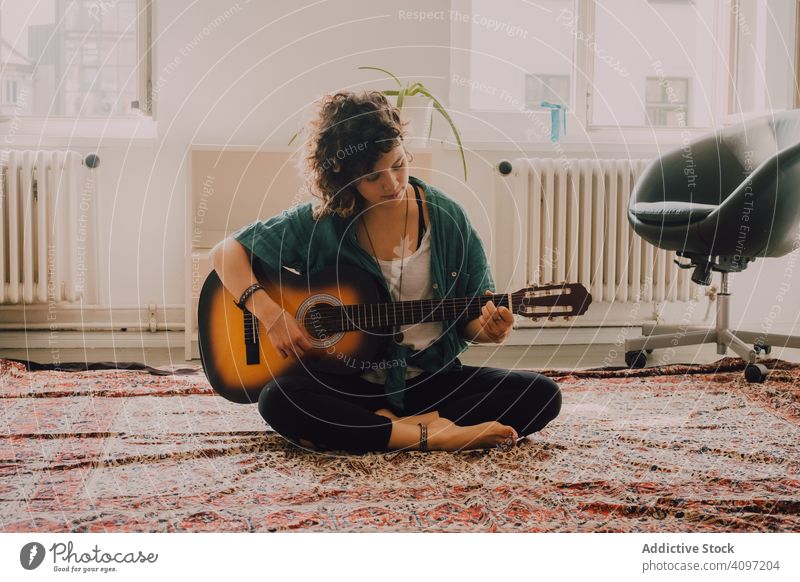 Zufriedene Frau spielt zu Hause Gitarre spielen Inhalt entspannt lässig akustisch minimalistisch Raum heimwärts Stock sitzen Musiker Gitarrenspieler