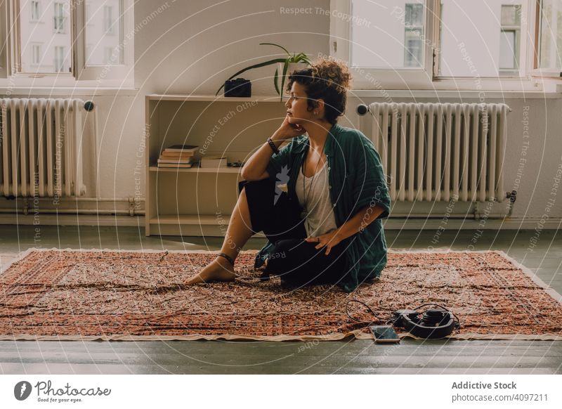 Friedliche Frau meditiert zu Hause auf dem Boden besinnlich meditierend friedlich entspannt lässig sitzen Stock Teppich heimwärts Appartement modern Smartphone