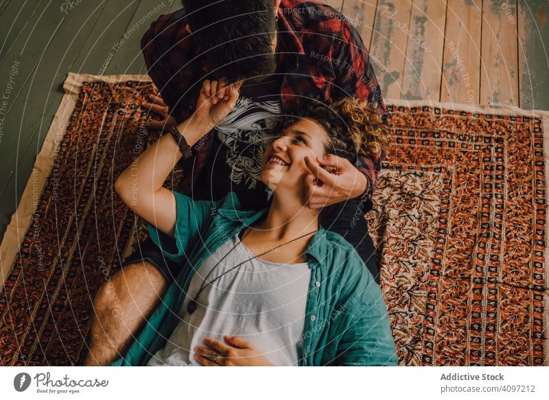 Glückliches Paar umarmt sich auf dem Teppich zu Hause Umarmen heimwärts freudig Lächeln lässig Umarmung Hipster modern Angebot Zuneigung Liebhaber Partnerschaft