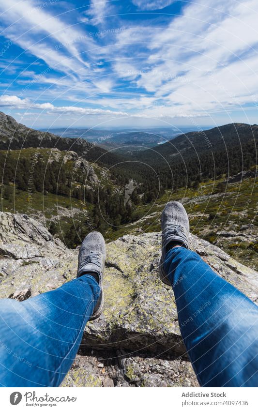Person sitzt mit baumelnden Beinen auf Stein über dem Bergtal Cloud Himmel Berge u. Gebirge Natur reisen Park Wald Tal Landschaft malerisch Hügel felsig
