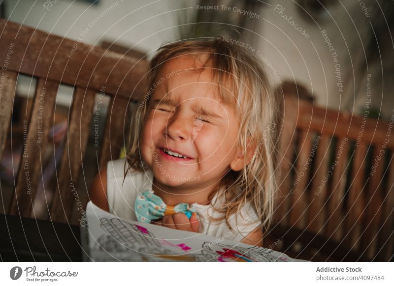 Kleines Mädchen, das blinzelt und auf eine Überraschung wartet warten Silberblick Lächeln heimwärts Malbuch sitzen gemütlich Raum Kind Lifestyle ruhen