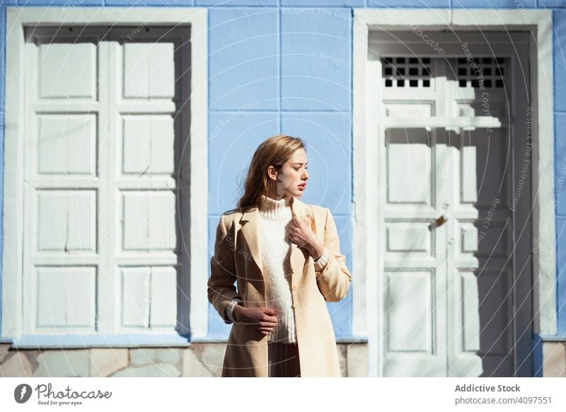 Sinnliche Frau, die ihr Gesicht vor der Sonne schützt, in der Nähe einer Tür stylisch Straße Gebäude sonnig Schutz jung sinnlich urban Mode Model cool trendy