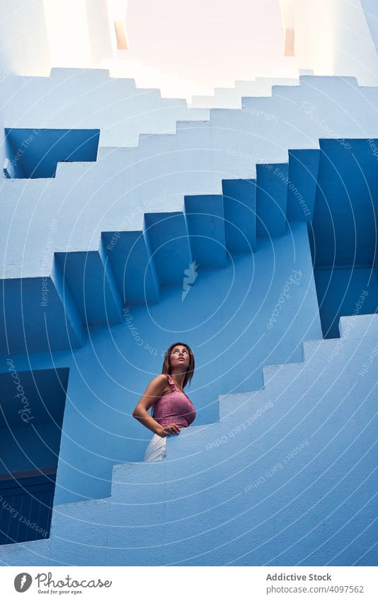Frau geht die Treppe hinauf zum modernen blauen Gebäude lange Haare laufen nach oben elegant Konstruktion Struktur geometrisch Architektur urban Fassade