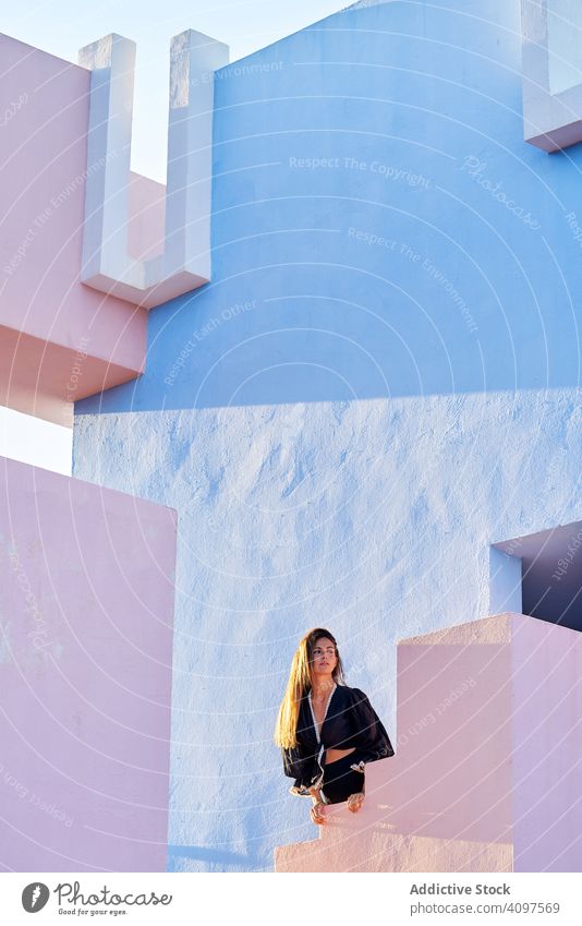 Frau steht auf einem modernen blauen Gebäude lange Haare Kleid schwarz elegant Stehen Barfuß Konstruktion Struktur geometrisch Architektur urban Fassade Zentrum